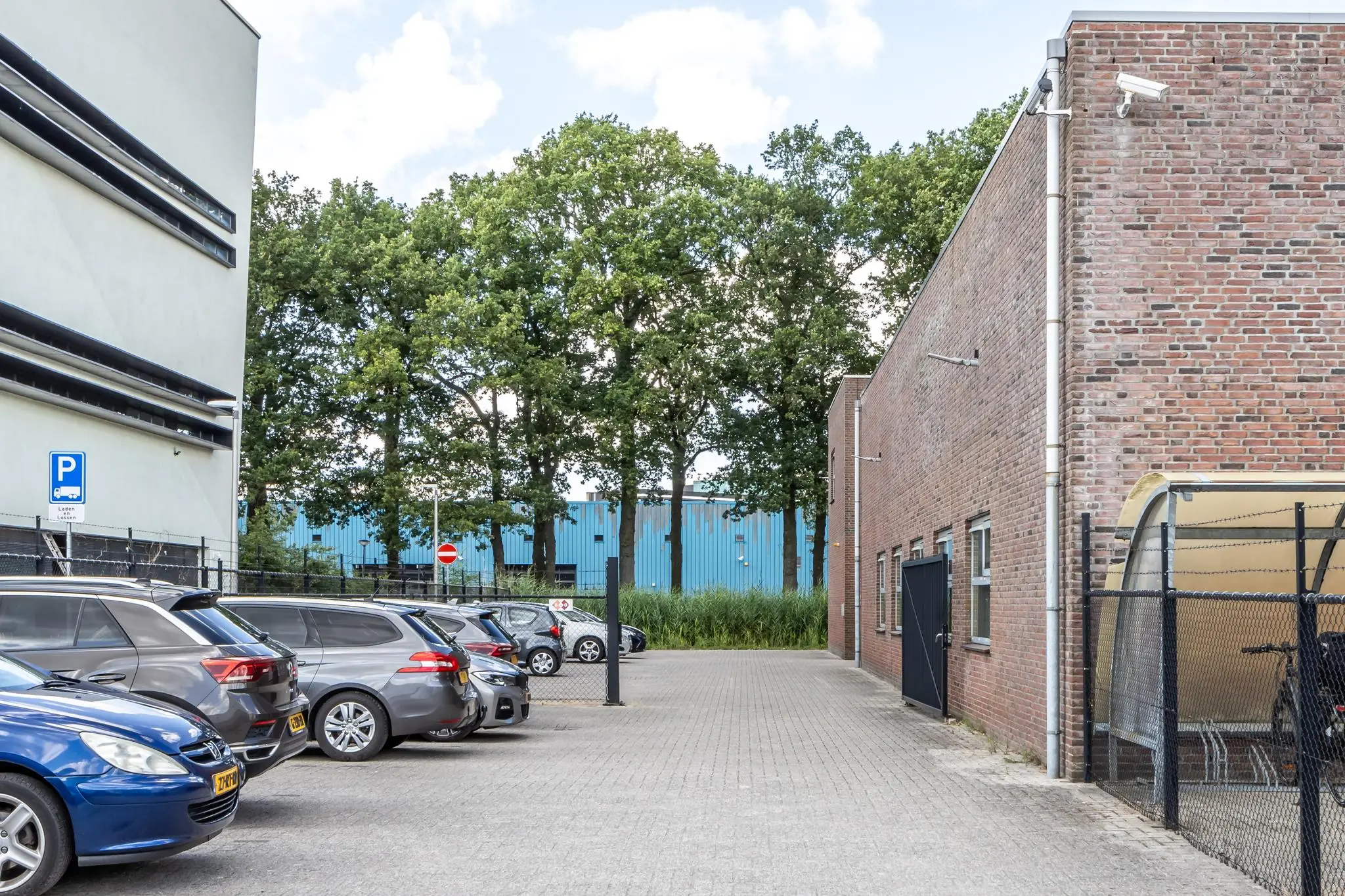 Parkeerplaats aan de Terminalweg met geparkeerde auto's, fietsenstalling en omliggende bedrijfsgebouwen.