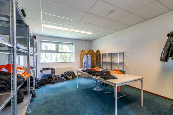 Kamer met metalen rekken, tafels en werkkleding in een bedrijfsruimte aan de Terminalweg.