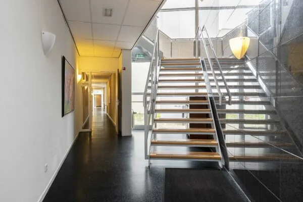 Moderne, lichte hal met een houten trap en een lange gang in een gebouw aan de Banningstraat.
