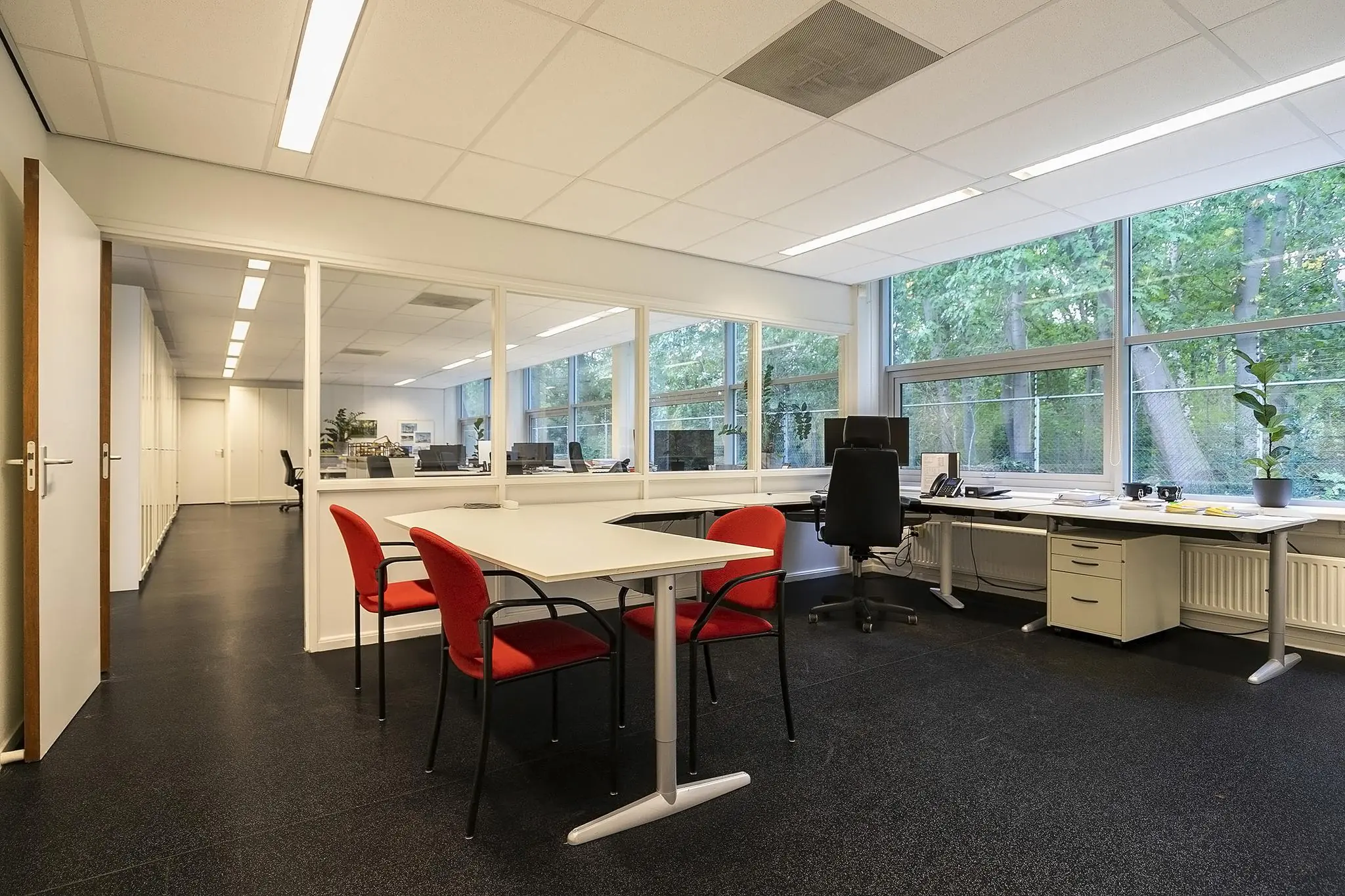 Modern ingericht kantoor aan de Banningstraat met werkplekken, vergadertafel en grote ramen met uitzicht op groen.