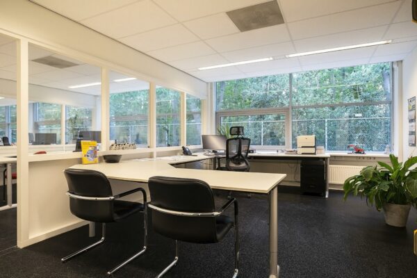 Modern kantoor aan de Banningstraat met strakke bureaus, glazen wanden en uitzicht op een groene buitenomgeving.