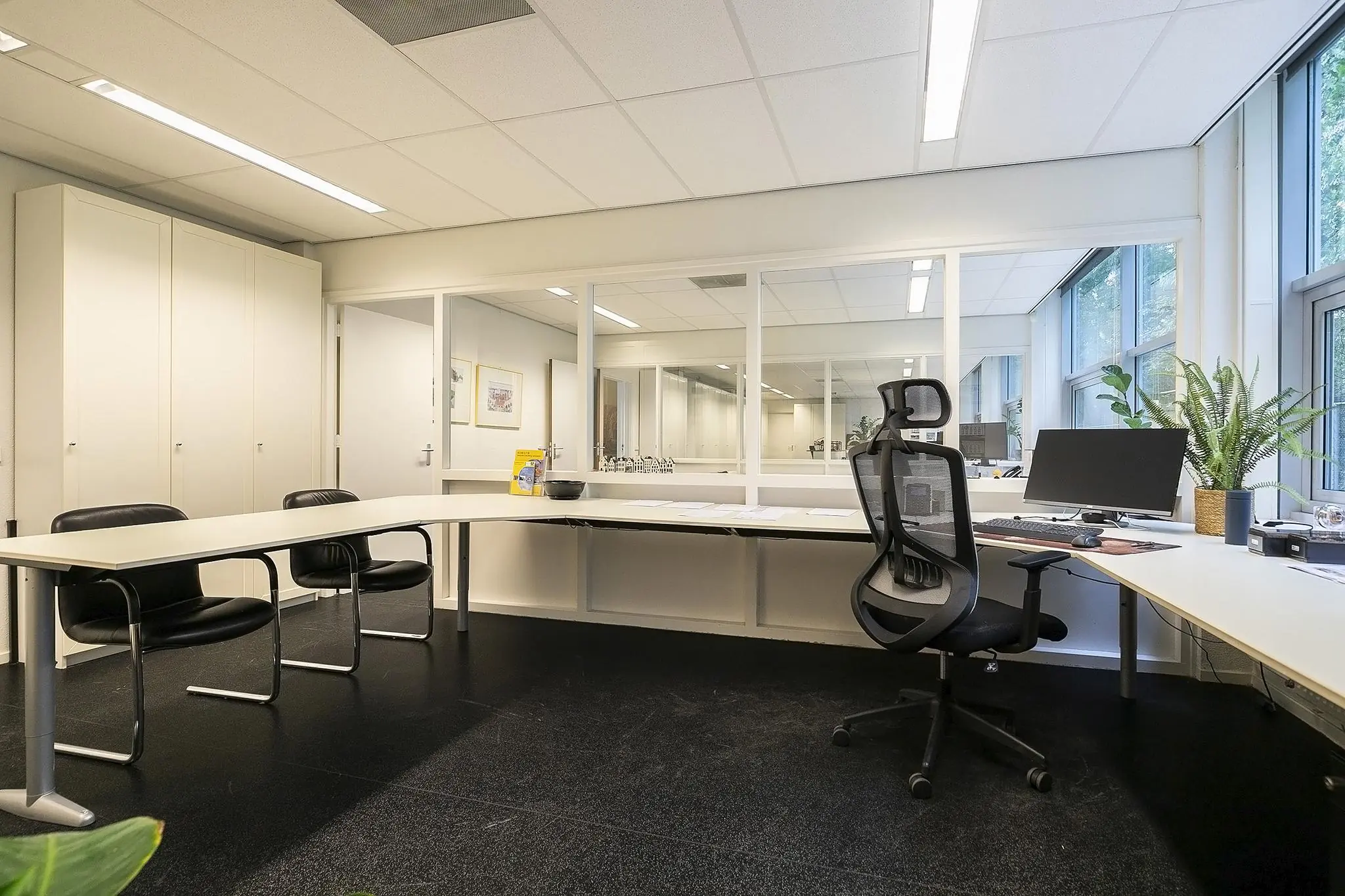 Modern ingericht kantoor aan de Banningstraat met bureau, bureaustoel, vergaderstoelen en grote ramen.