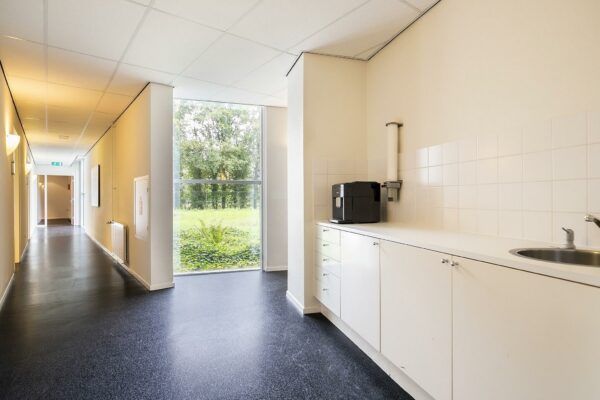 Gang met pantry inclusief koffieautomaat en aanrechtblad in een licht en modern gebouw aan de Banningstraat.