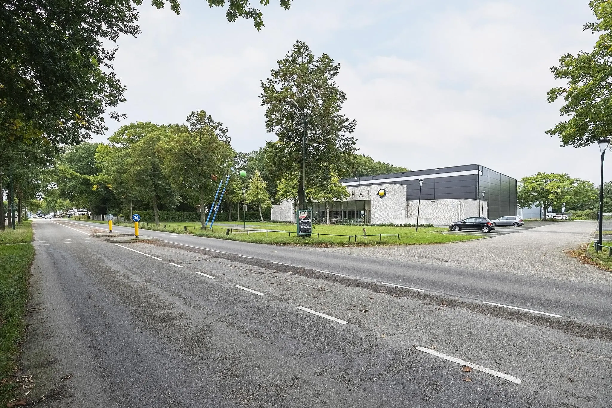 Moderne sporthal aan de Banningstraat met parkeerplaatsen en omliggend groen.