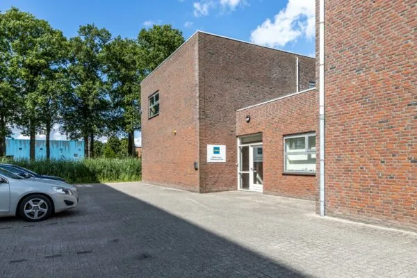 Bakstenen kantoorgebouw aan de Terminalweg met ingang van ARBN Assen Trainingscentrum en geparkeerde auto's op de voorgrond.