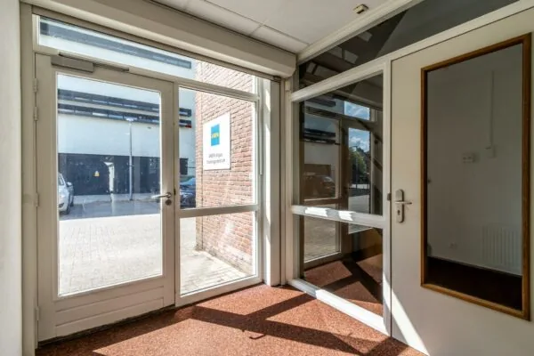 Ingang van het AREPA Applus Trainingscentrum aan de Terminalweg met glazen deuren en uitzicht op de parkeerplaats.