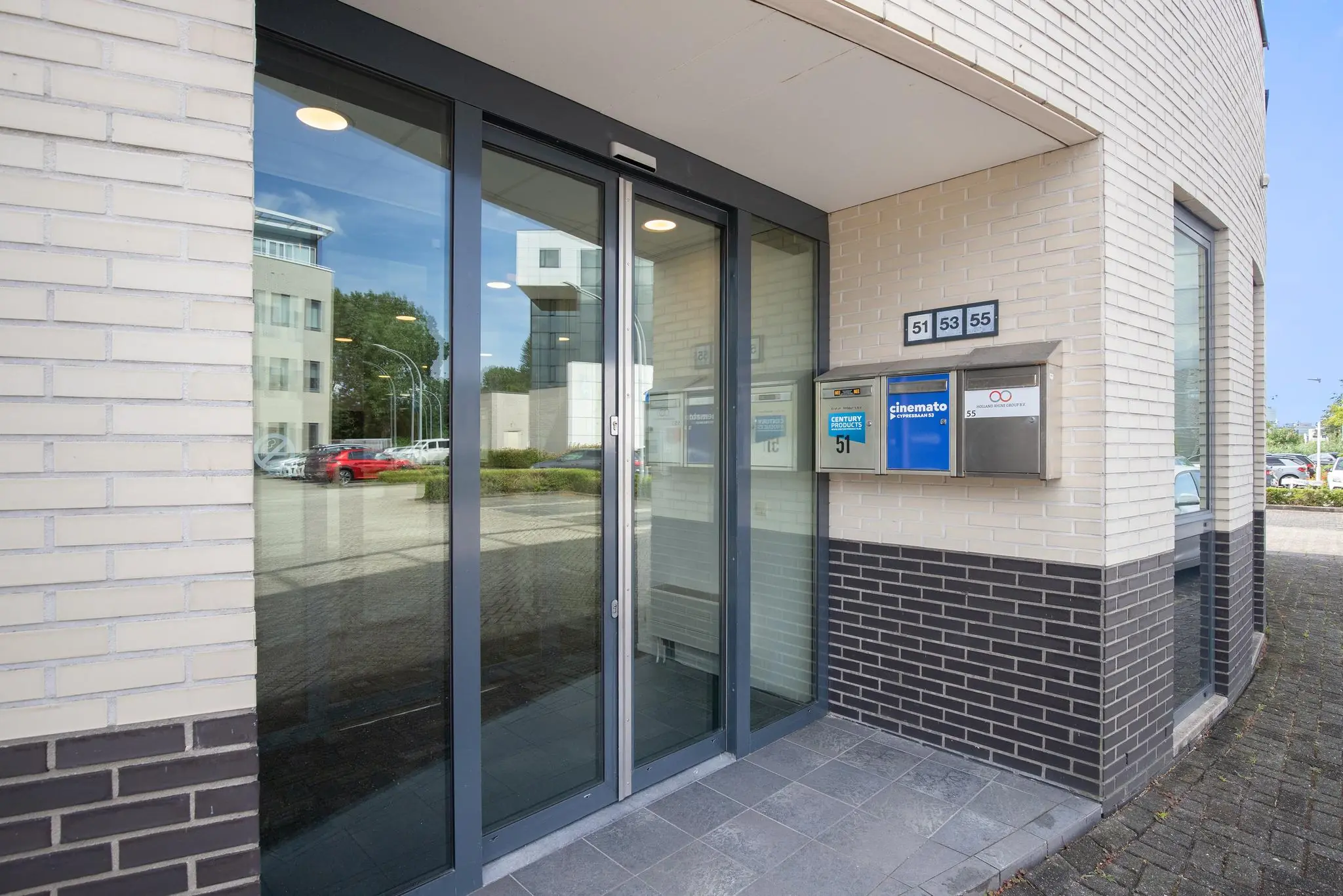 Glazen entree van een kantoorpand aan de Cypresbaan met brievenbussen voor de nummers 51, 53 en 55.
