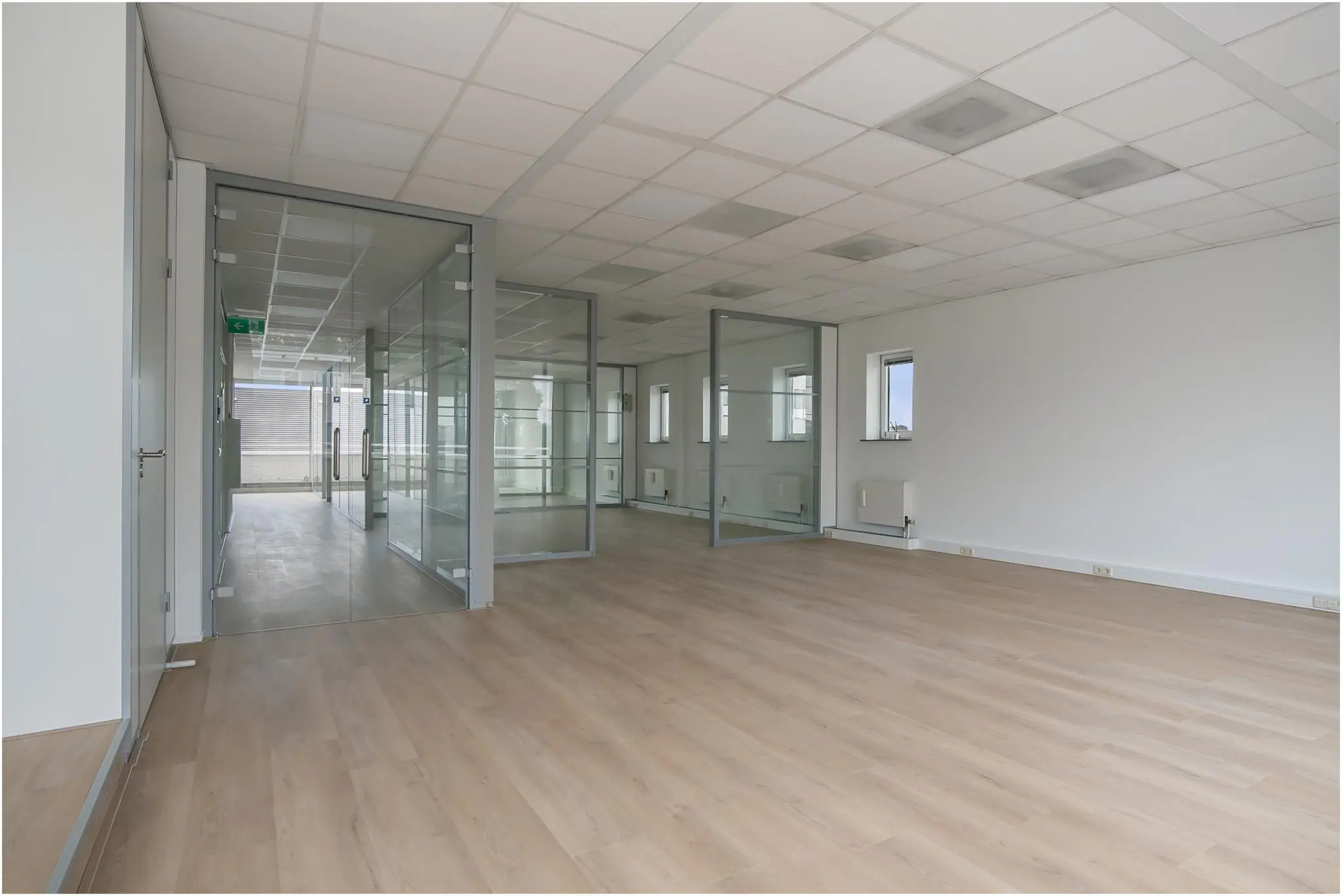 Leeg modern kantoorpand aan de Cypresbaan met glazen wanden en houtlook vloer.