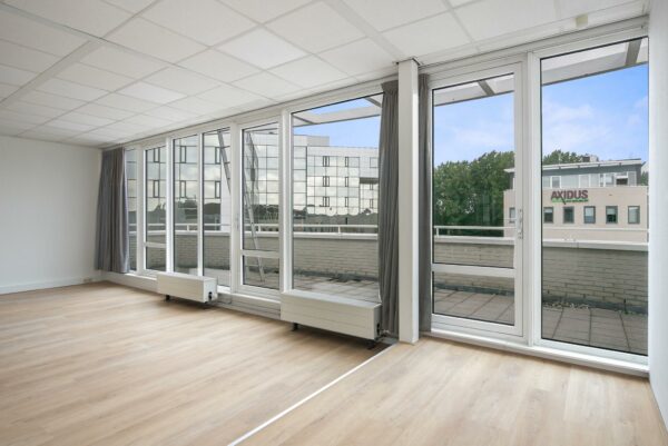 Lichte, leegstaande kantoorruimte aan de Cypresbaan met grote ramen en uitzicht op het Axidus-gebouw.