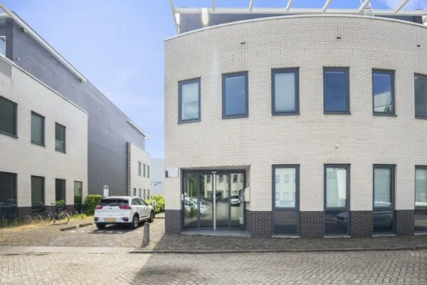 Vooraanzicht van een modern kantoorgebouw aan de Cypresbaan met parkeerplaats en fietsenrekken.