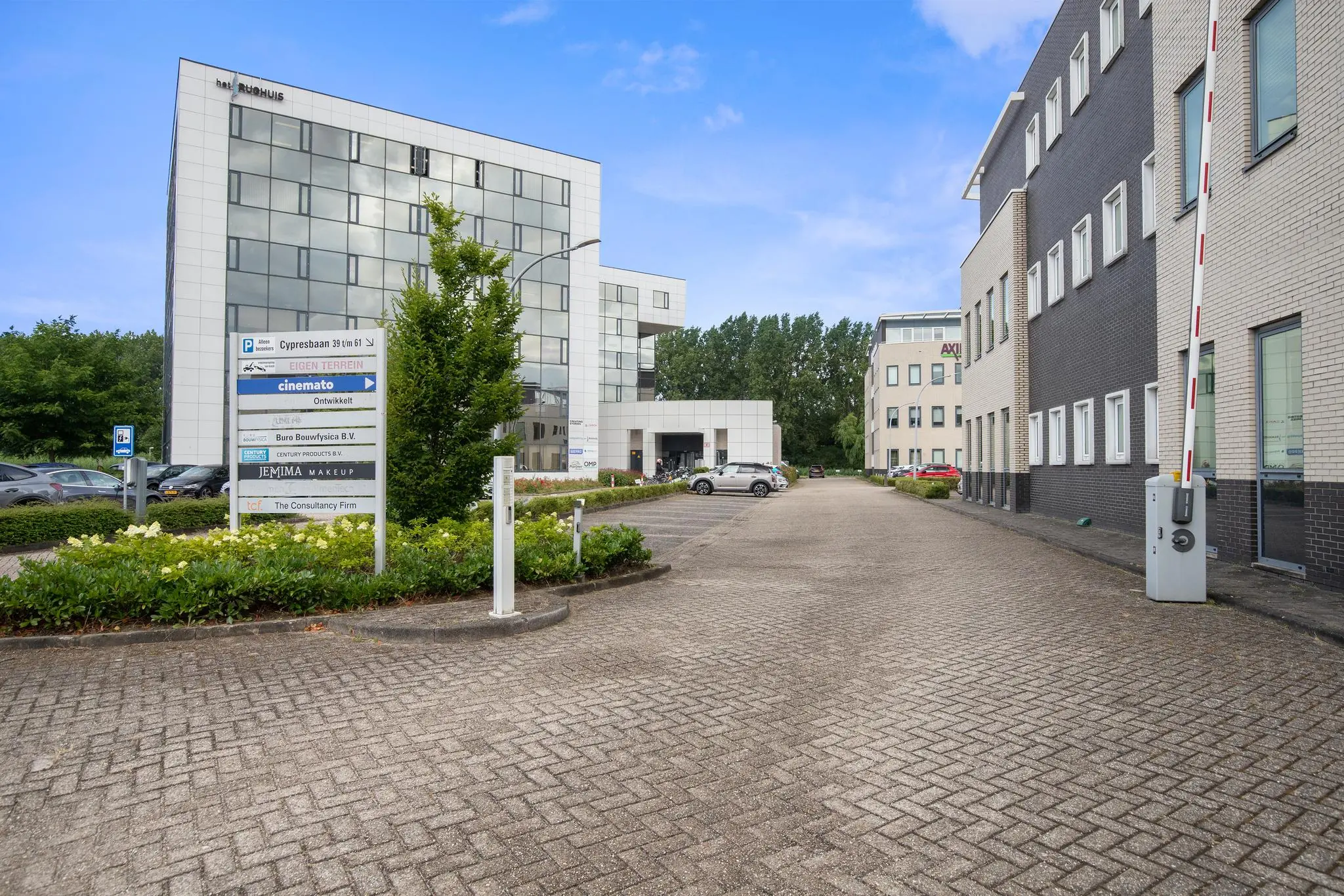 Ingang van een modern bedrijvenpark aan de Cypresbaan met kantoorpanden en een bord met bedrijfsnamen.