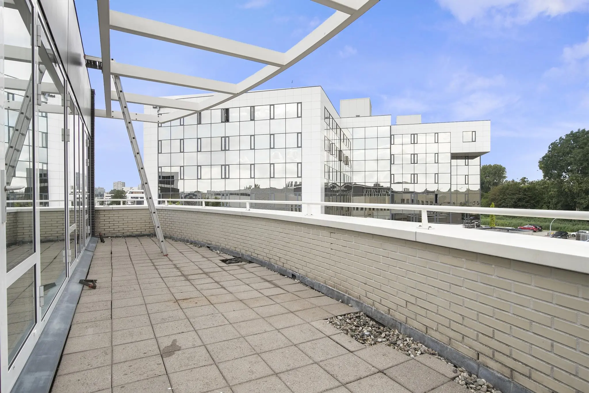 Ruim betegeld dakterras aan de Cypresbaan met uitzicht op moderne kantoorgebouwen met spiegelende gevels.