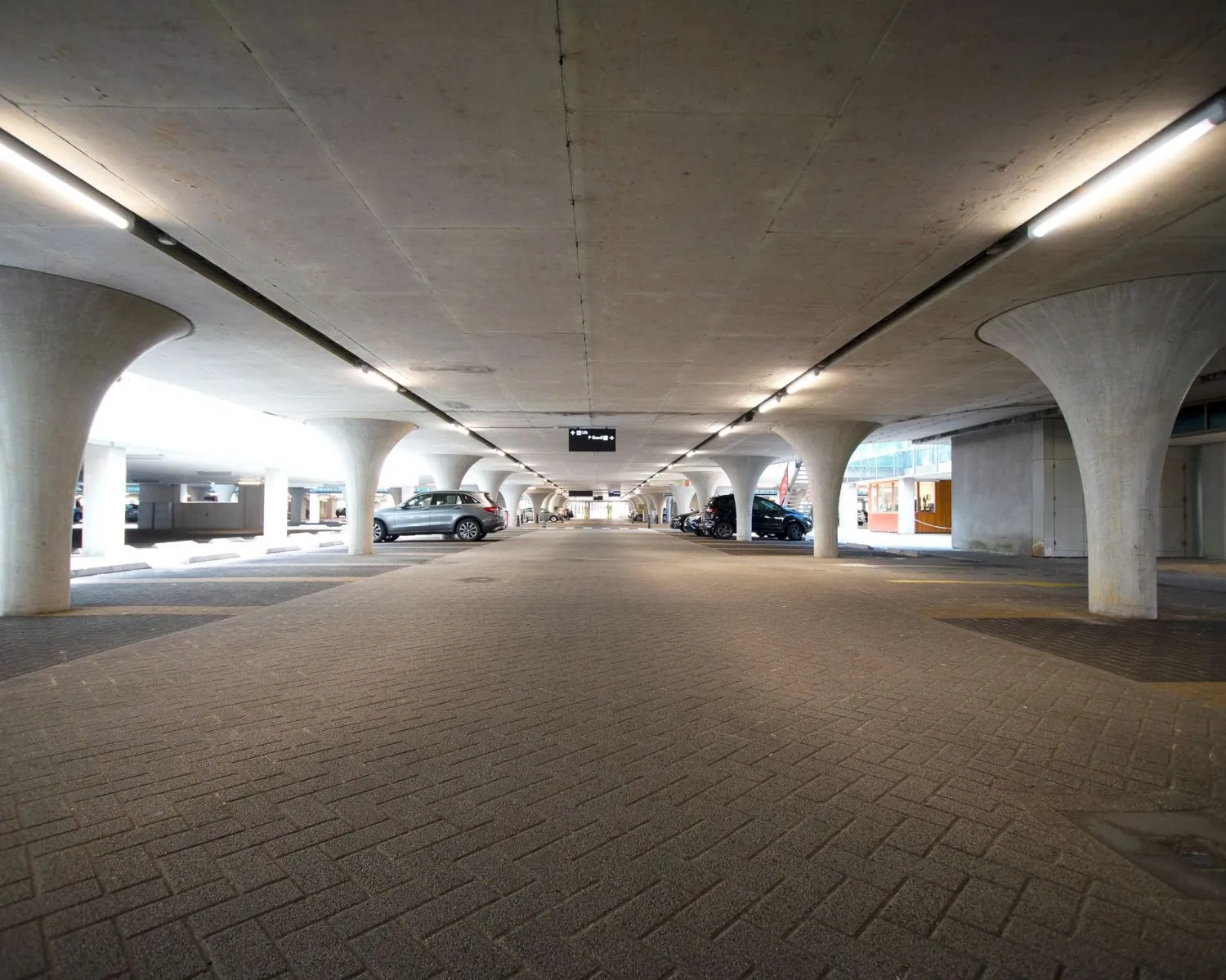 Overdekte parkeergarage onder het kantoorgebouw aan de Herikerbergweg 288-290 in Amsterdam met geparkeerde auto's en betonnen kolommen.