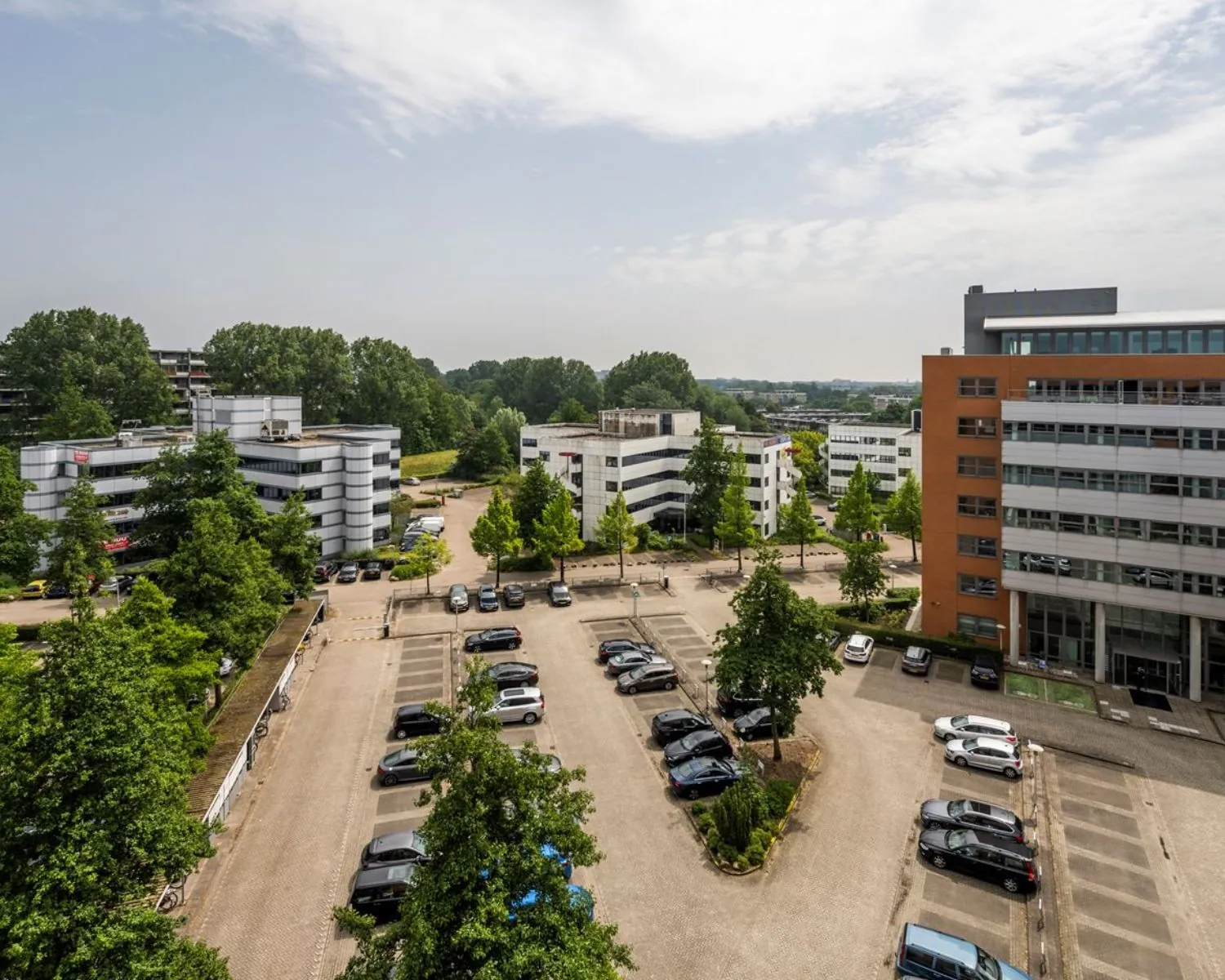 Luchtfoto van kantoorcomplex Entrada 300 in Amsterdam met parkeerplaatsen en omliggende kantoorgebouwen.