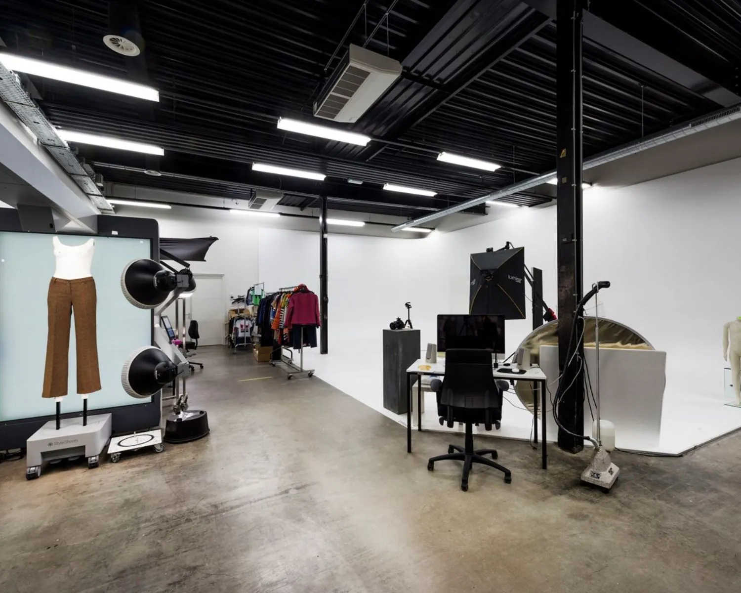 Moderne kantoorruimte in Diemen ingericht als fotostudio met apparatuur, kledingrekken en werkplek.