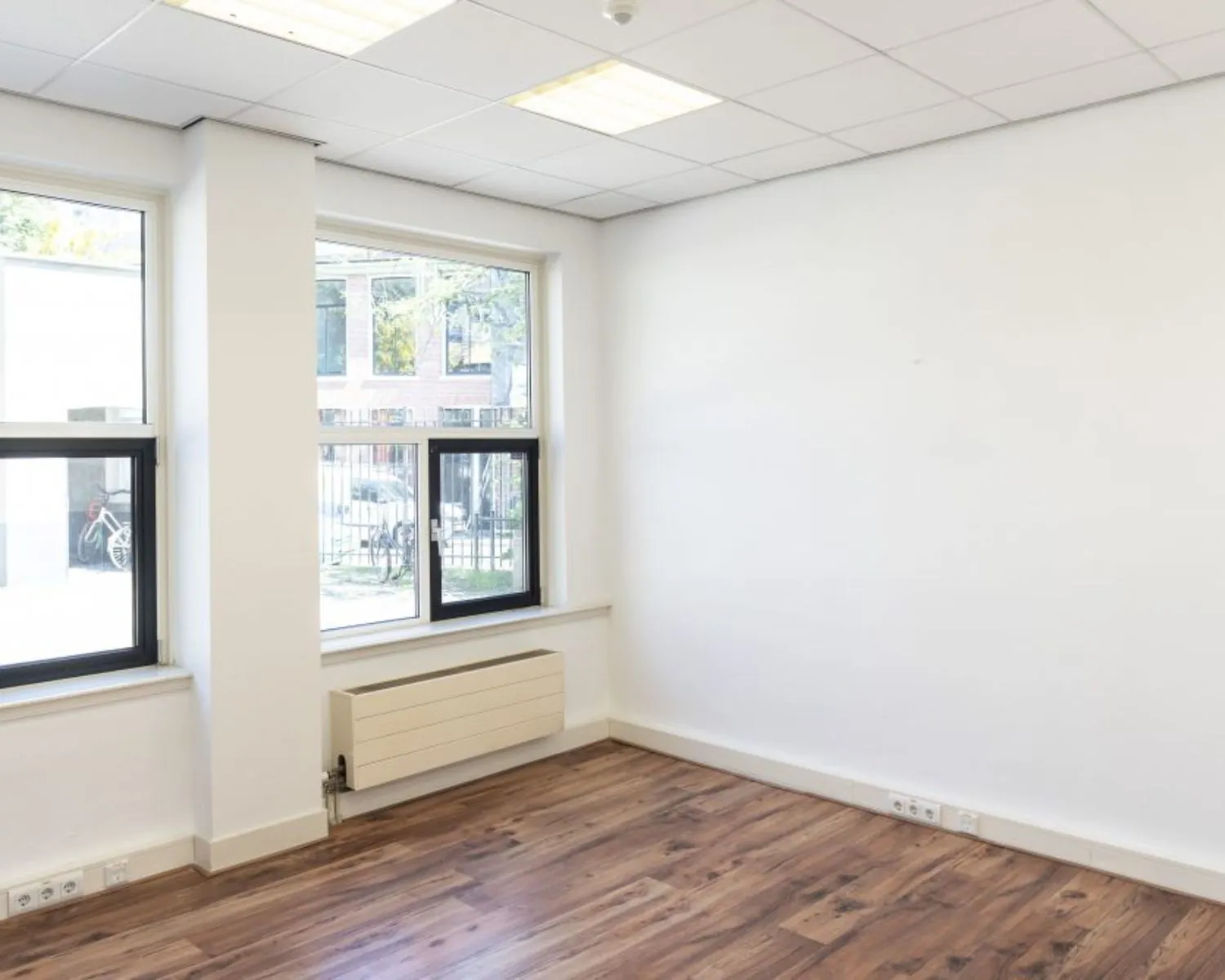 Lichte kantoorruimte met houten vloer en grote ramen aan de Wilhelminastraat 43A in Haarlem.