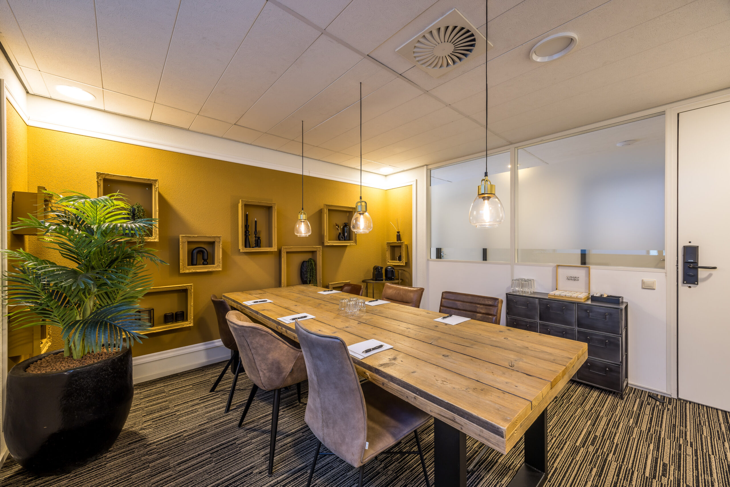 Vergaderruimte bij Element Offices met houten tafel, bruine stoelen en hanglampen aan het plafond.