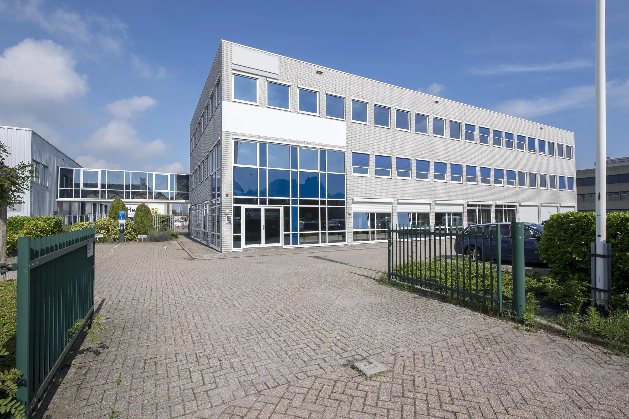 Wit kantoorgebouw met grote ramen en parkeerplaats aan de Witboom in een industriële omgeving.