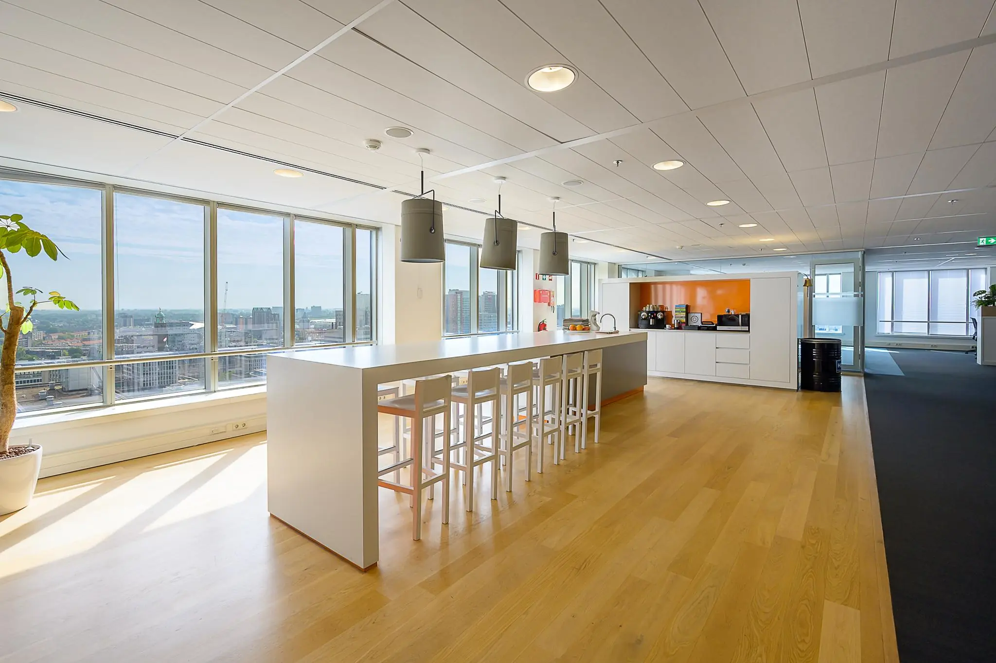 Moderne kantoorkeuken aan het Weena met een lange tafel, barkrukken en uitzicht over de stad.