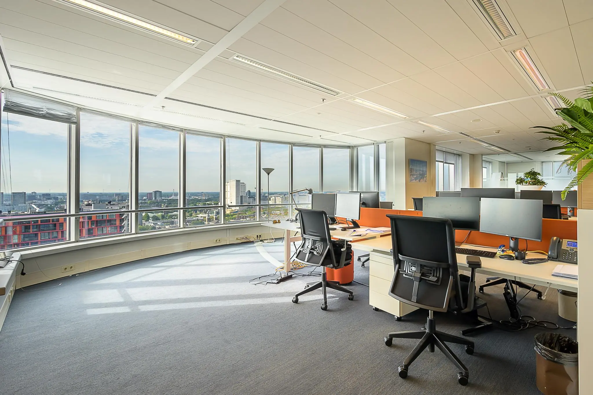 Modern kantoor met werkplekken, grote ramen en uitzicht over de stad aan de Weena in Rotterdam.