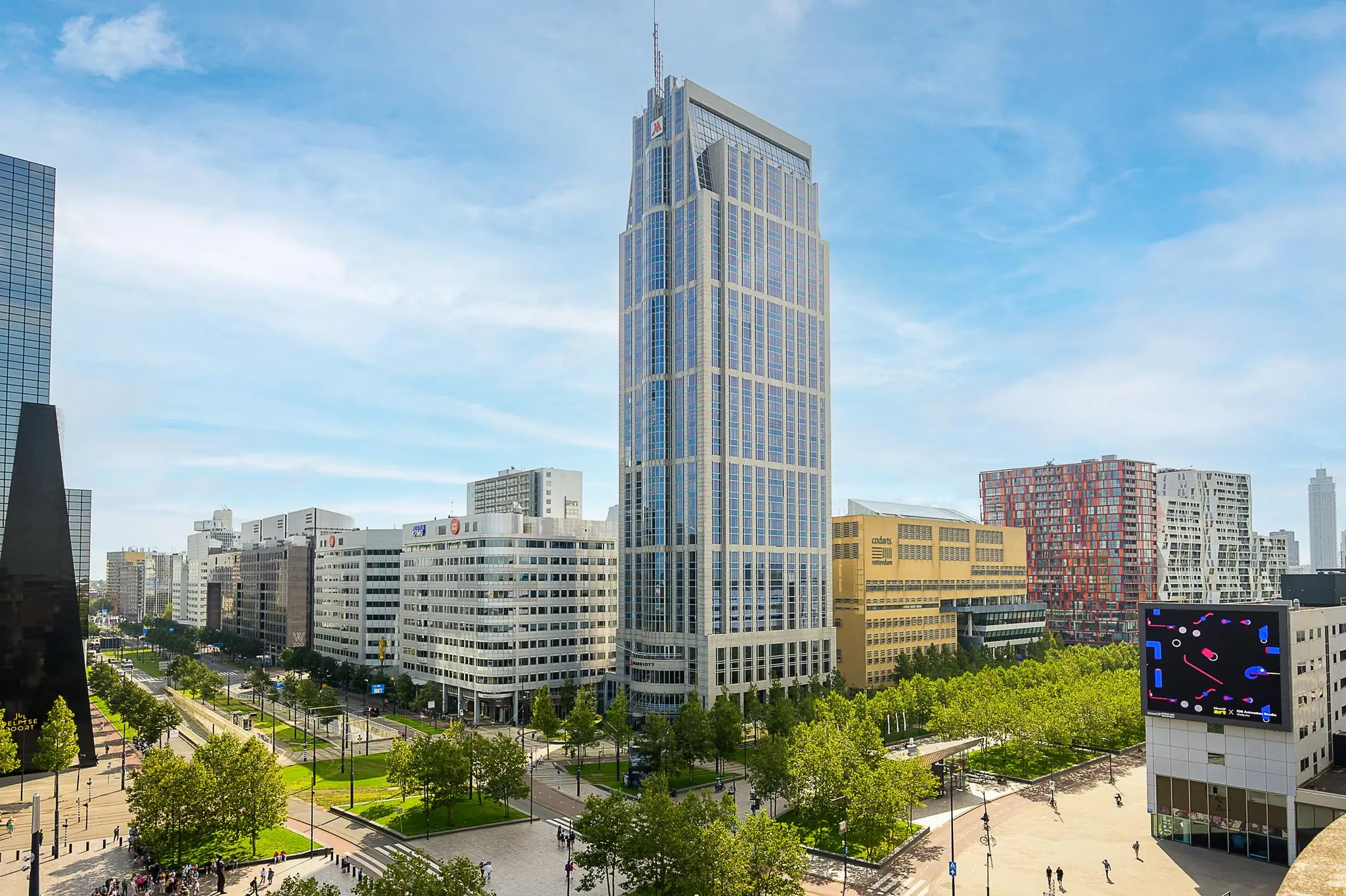 Hoog kantoorgebouw aan het Weena in Rotterdam met omliggende moderne architectuur en groene stadsomgeving.