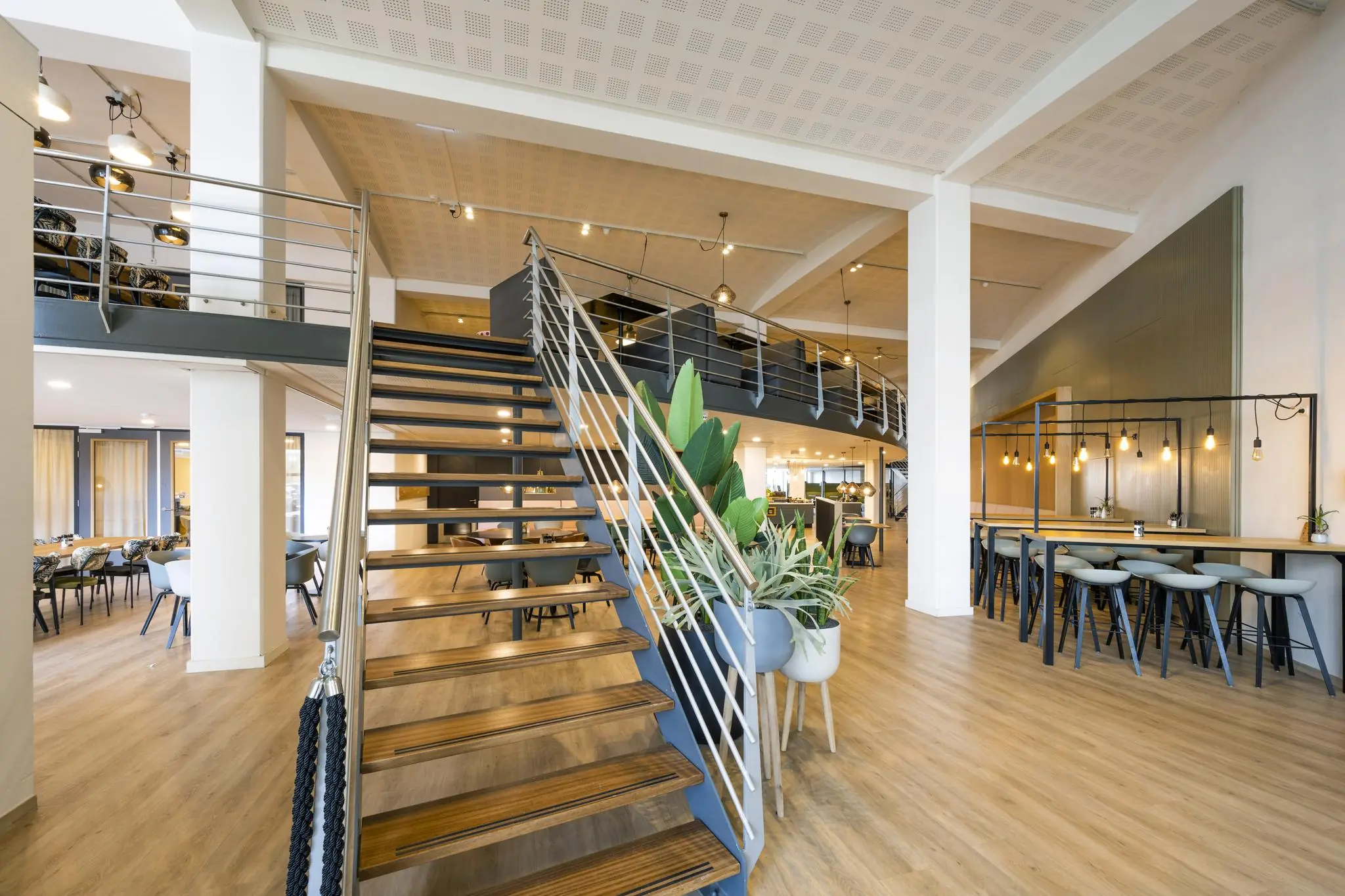 Moderne kantoorruimte aan de Kabelweg met een houten trap, planten en een stijlvolle zithoek.