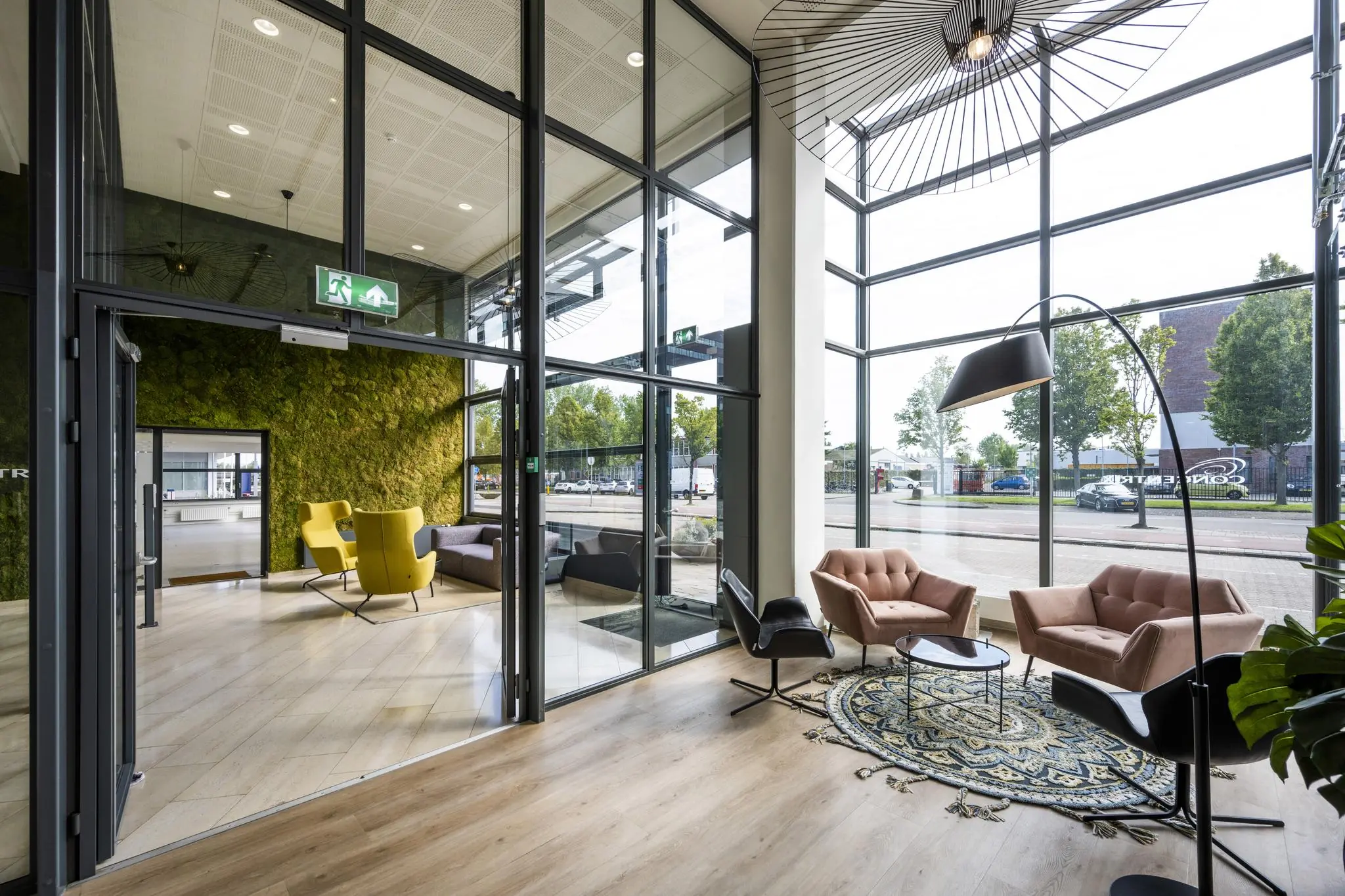 Moderne, lichtovergoten lobby aan de Kabelweg met comfortabele zitplekken, grote ramen en een groene moswand.