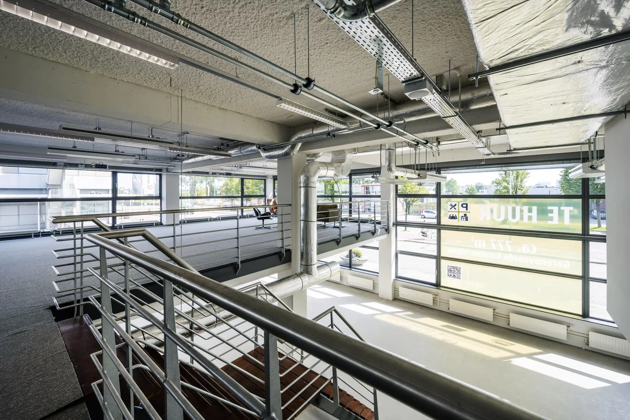 Modern kantoorinterieur aan de Kabelweg met een industriële uitstraling, grote ramen en zicht op een te huur-bord.