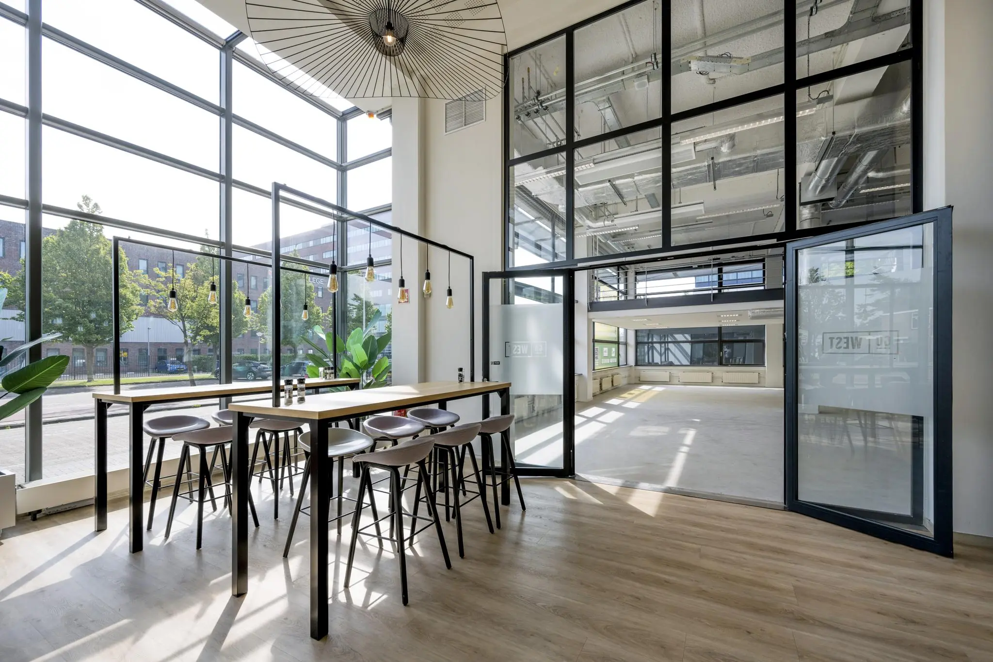Moderne, lichte kantoorruimte aan de Kabelweg met hoge ramen, houten vloer en een industriële uitstraling.