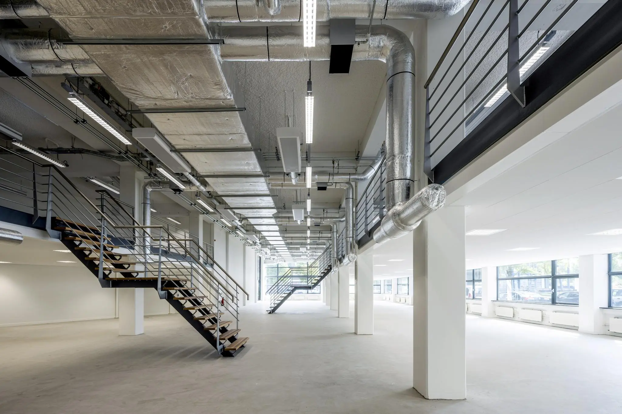 Ruimtelijk, modern kantoorpand aan de Kabelweg met industriële afwerking en metalen trappen.