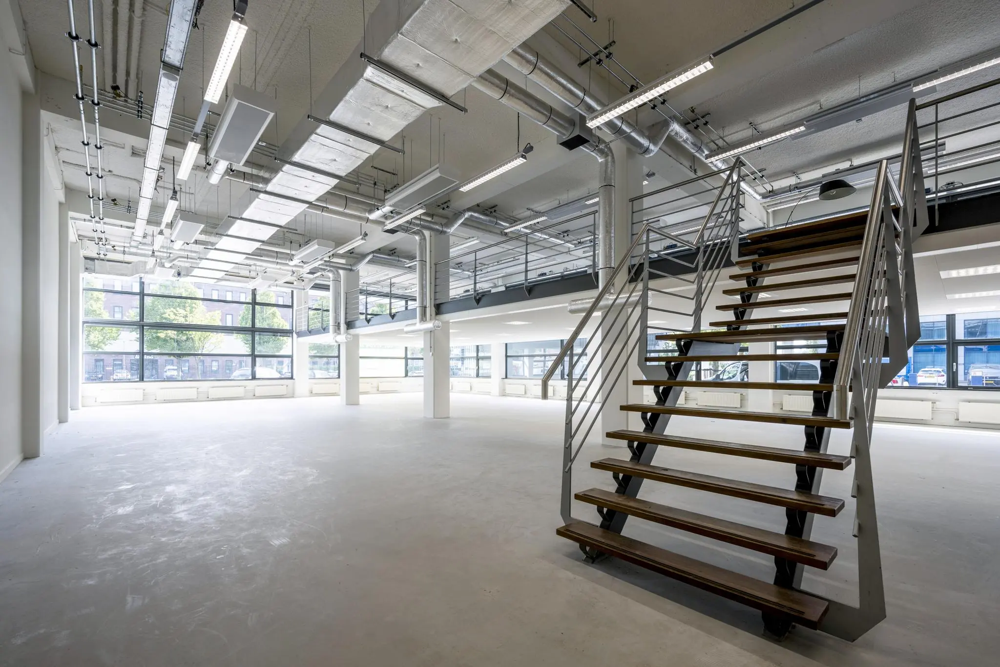 Moderne, industriële kantoorruimte aan de Kabelweg met open indeling, grote ramen en een metalen trap.