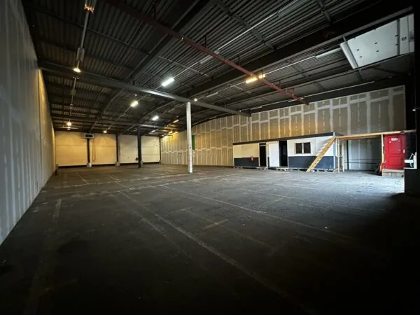 Lege bedrijfshal aan de Locomotiefstraat met een tijdelijke kantoorunit en een betonnen vloer.