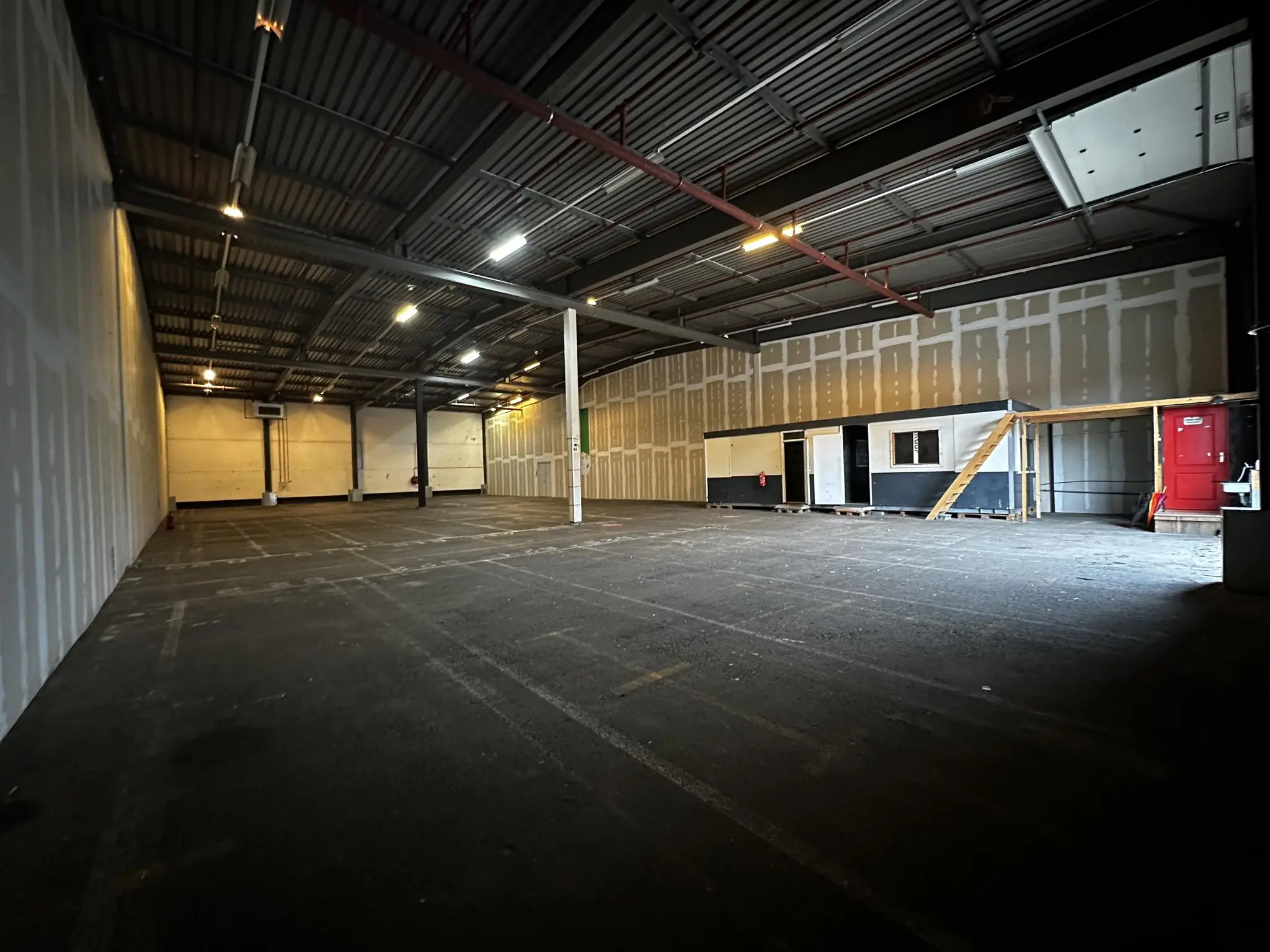Lege bedrijfshal aan de Locomotiefstraat met een tijdelijke kantoorunit en een betonnen vloer.