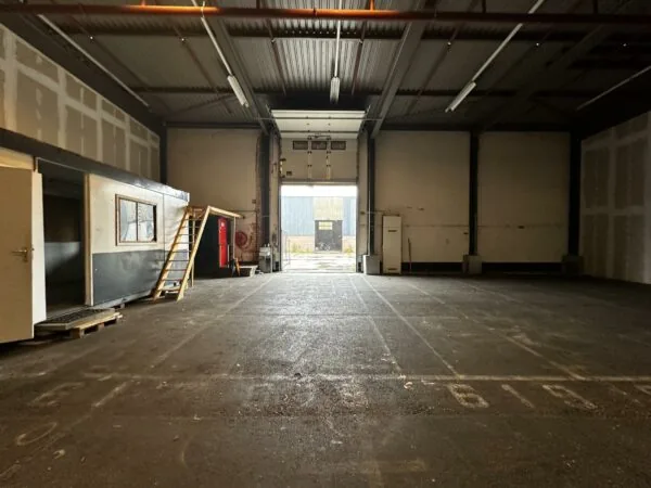Leegstaand magazijn aan de Locomotiefstraat met een open roldeur en een kantoorunit met trap.