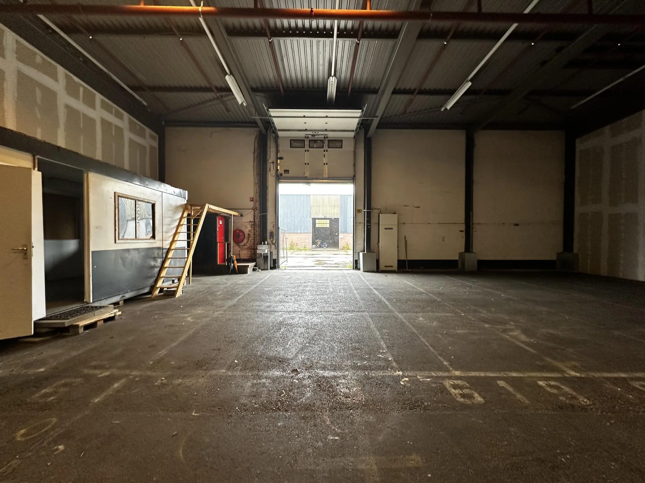 Leegstaand magazijn aan de Locomotiefstraat met een open roldeur en een kantoorunit met trap.