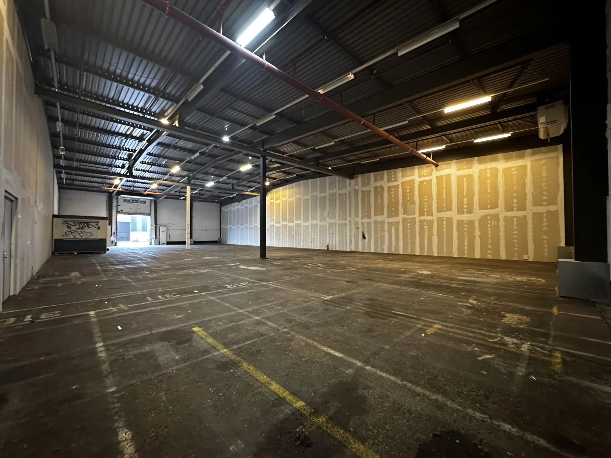 Lege bedrijfsruimte aan de Locomotiefstraat met onafgewerkte muren en zicht op een roldeur aan de achterzijde.