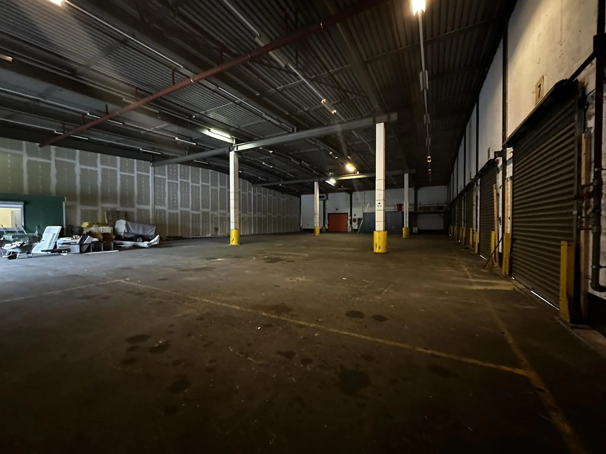 Lege industriële loods aan de Locomotiefstraat met betonnen vloer, hoge plafonds en meerdere opslagdeuren.