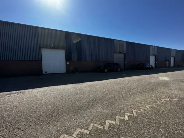 Bedrijfsloodsen aan de Locomotiefstraat met geparkeerde auto's en fietsen op een zonnige dag.