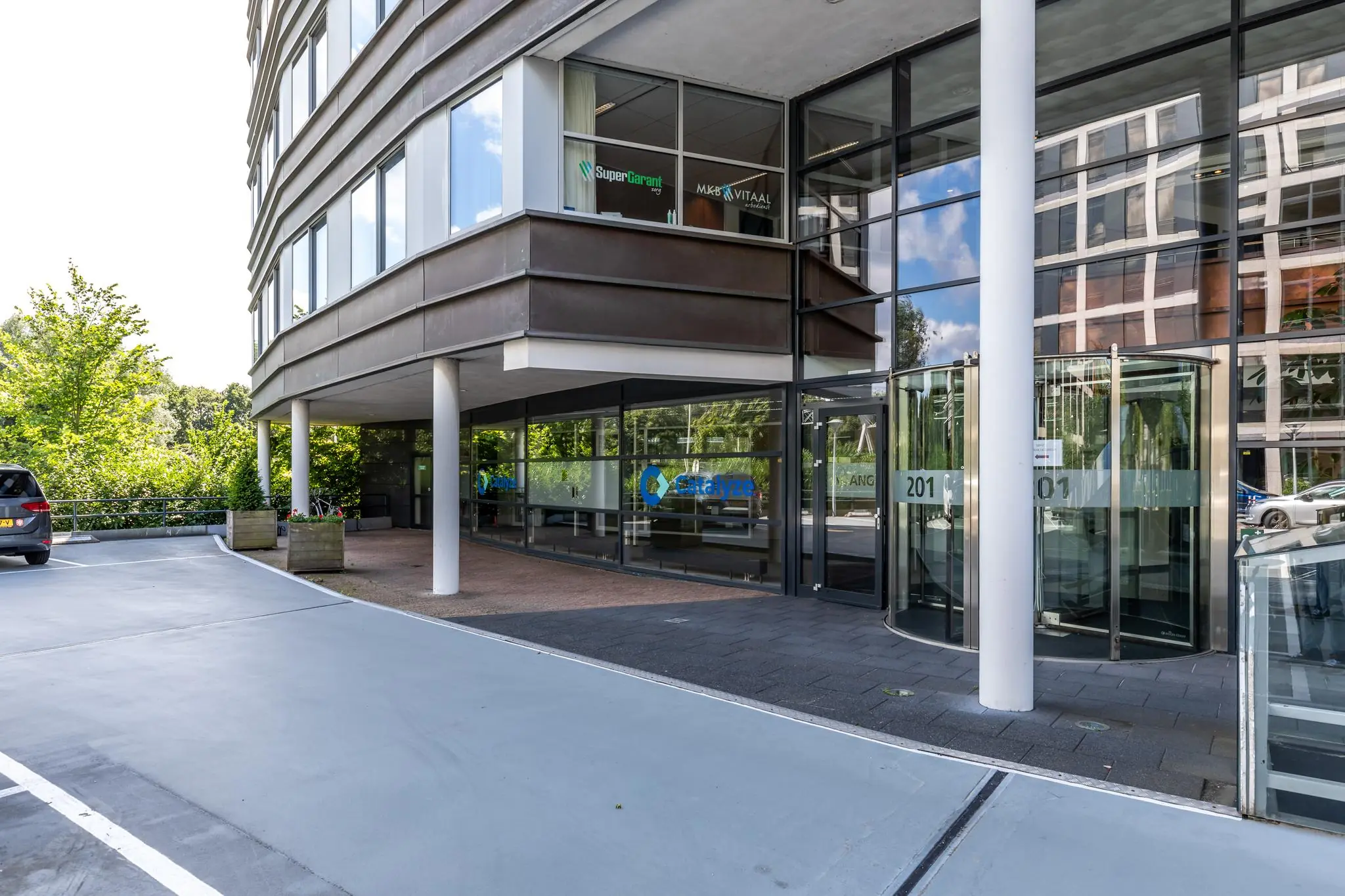 Ingang van een modern kantoorgebouw aan de Euclideslaan 201 met glazen draaideur en bedrijfsnamen op de ramen.