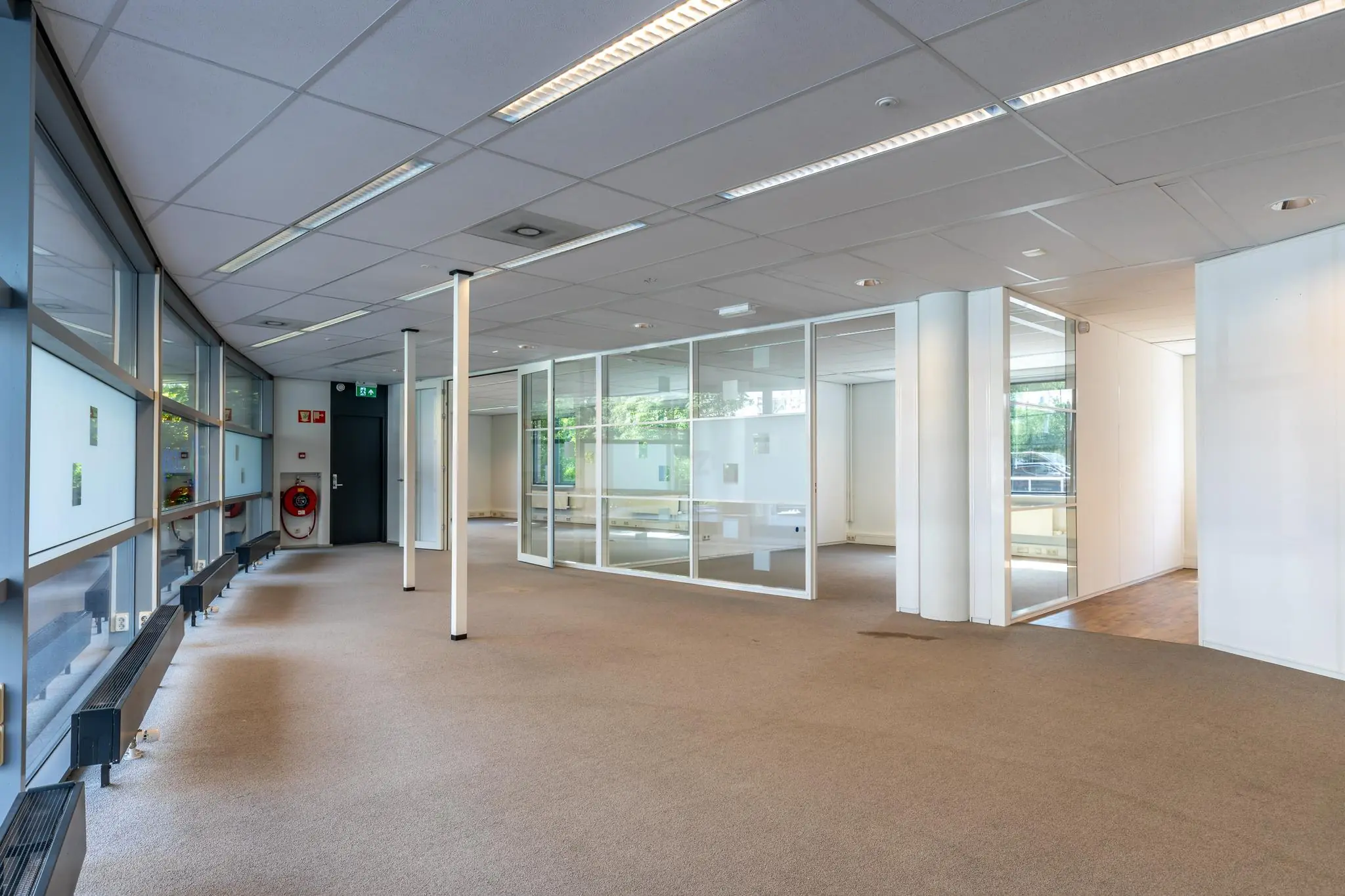 Leeg kantoorpand aan de Euclideslaan met glazen scheidingswanden en grote ramen.