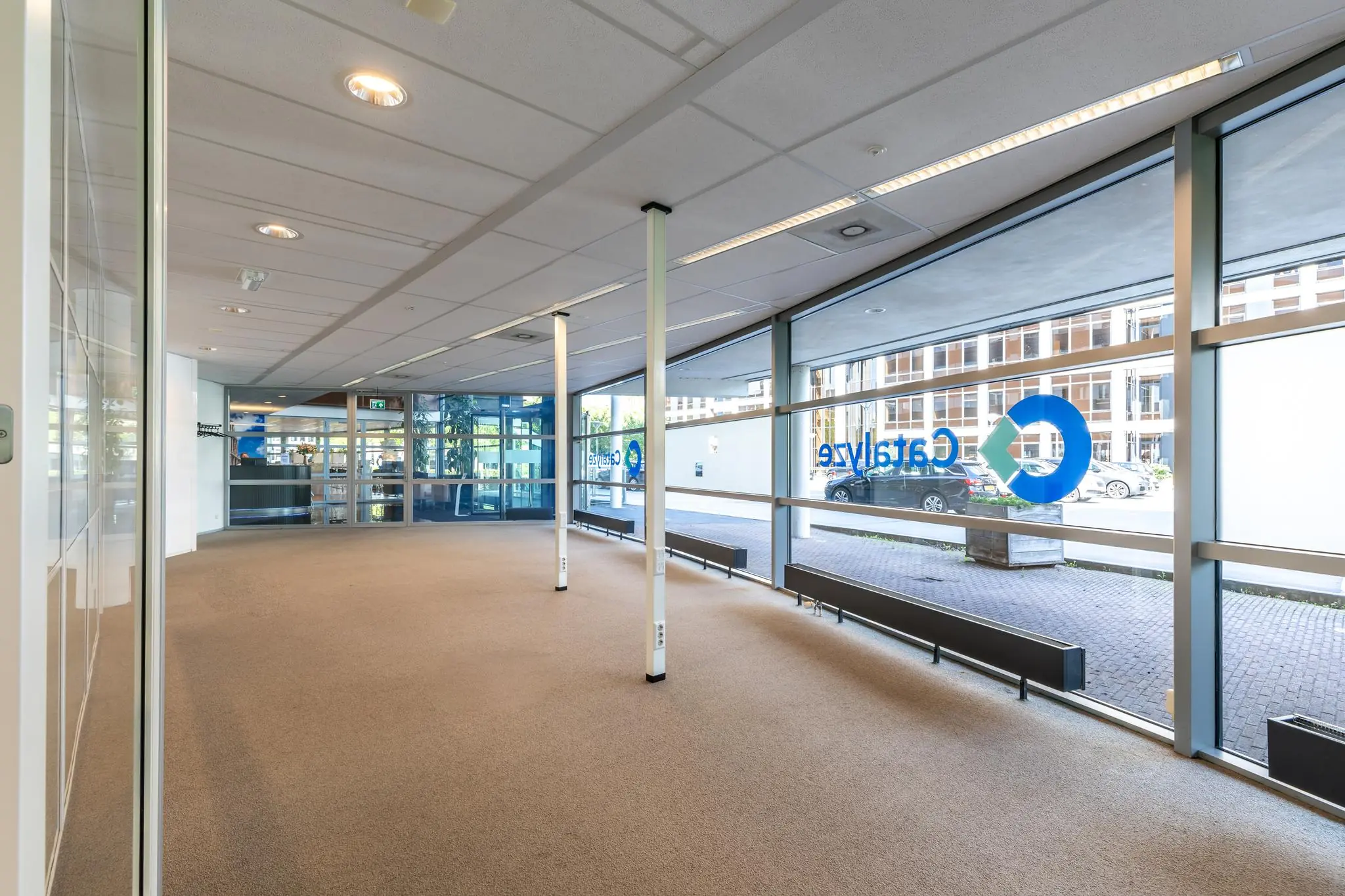 Lichte, lege kantoorruimte aan de Euclideslaan met grote ramen en uitzicht op de straat en het Catalyze-logo.