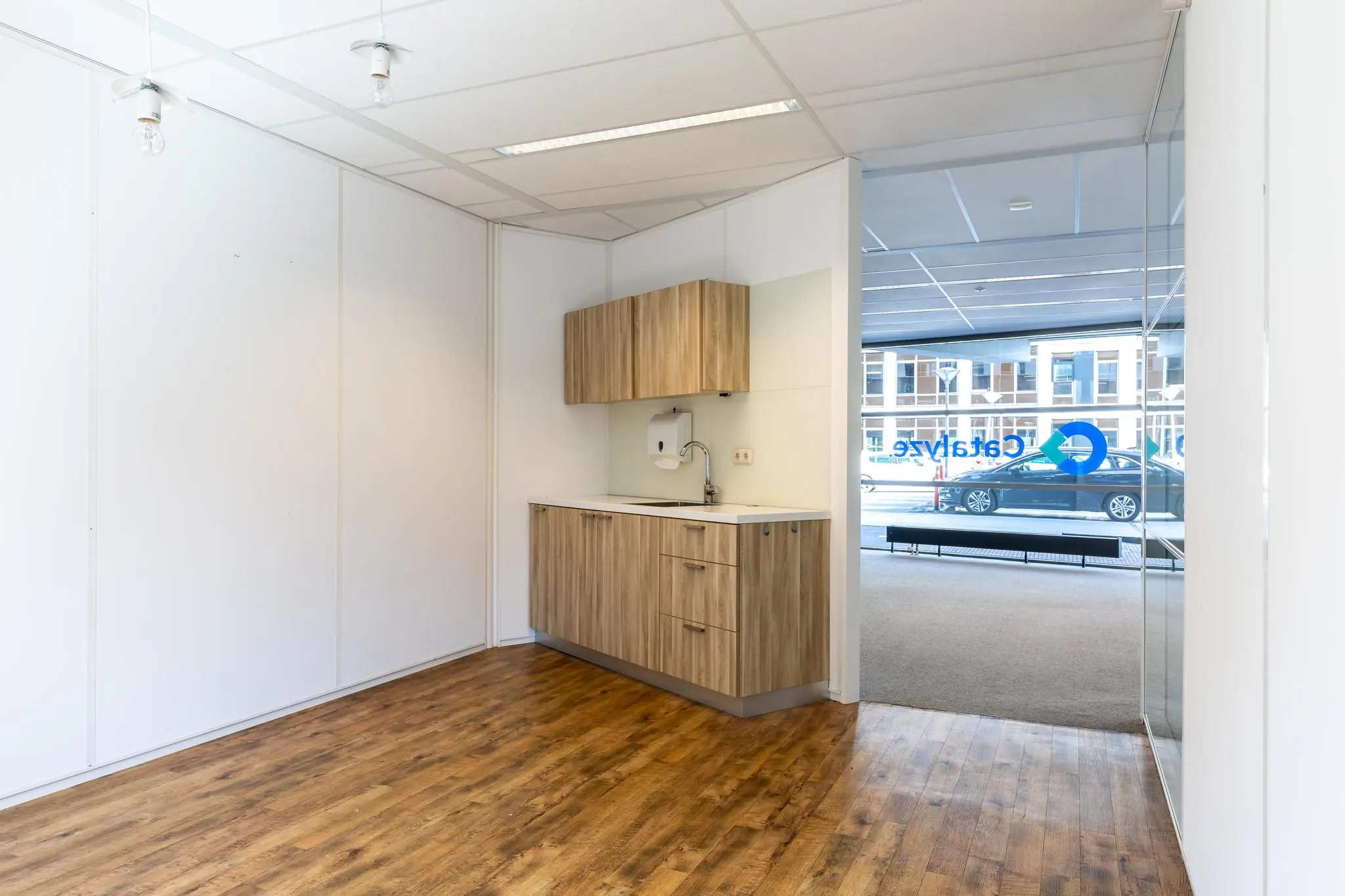 Kleine kitchenette met houtlook kastjes in een lichte kantoorruimte aan de Euclideslaan.