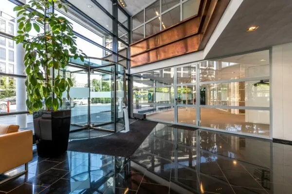 Moderne entreehal met glazen draaideur, grote raampartijen en een glanzende tegelvloer aan de Euclideslaan.