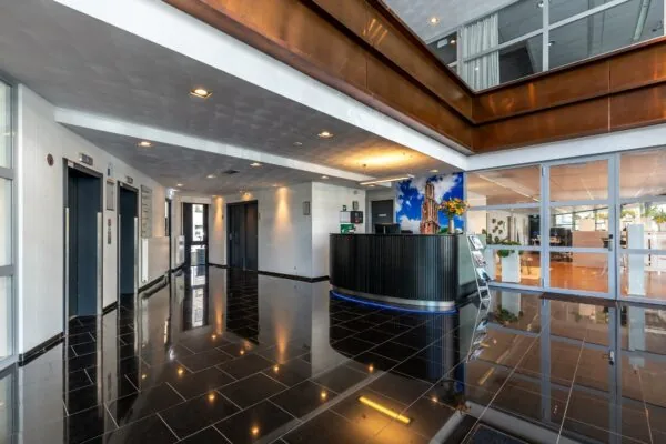 Moderne ontvangsthal met zwarte tegelvloer, receptiebalie en meerdere liften in een kantoorgebouw aan de Euclideslaan.