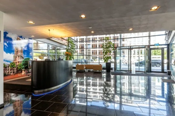 Moderne en lichte entreehal van een kantoorpand aan de Euclideslaan met receptiebalie, zitgedeelte en grote glazen draaideur.