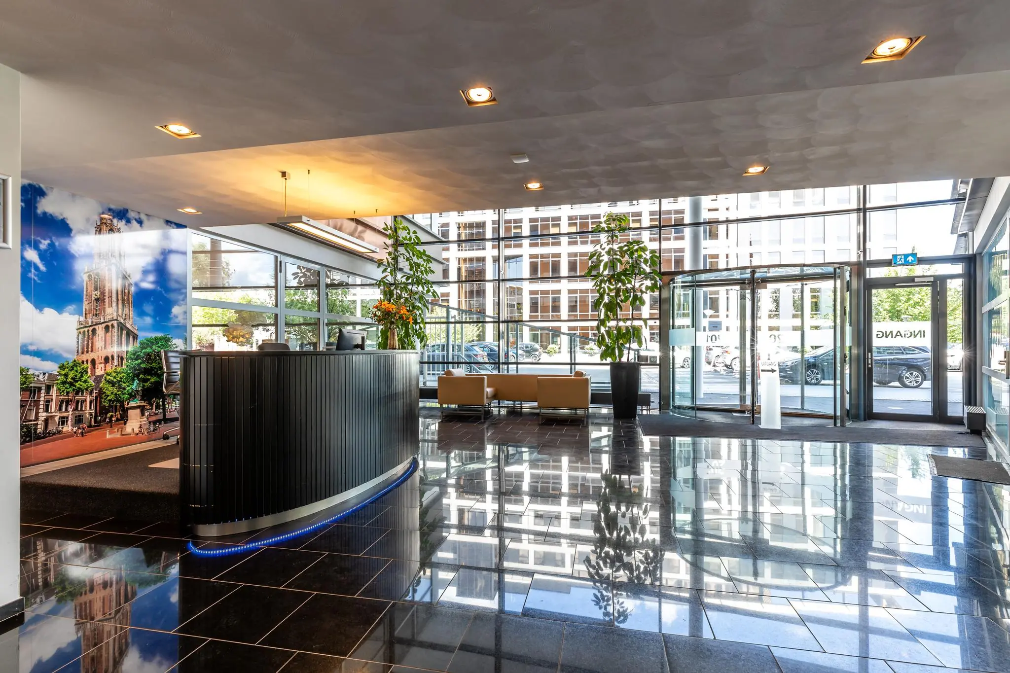Moderne en lichte entreehal van een kantoorpand aan de Euclideslaan met receptiebalie, zitgedeelte en grote glazen draaideur.