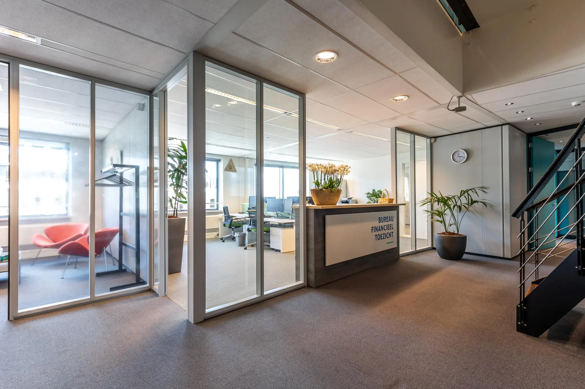 Moderne kantoorruimte van Bureau Financieel Toezicht met glazen wanden, een receptiebalie en een zithoek.
