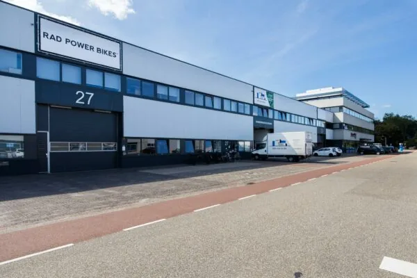 Bedrijfsverzamelgebouw aan de Zonnebaan met onder andere Rad Power Bikes en meerdere geparkeerde voertuigen voor de ingang.