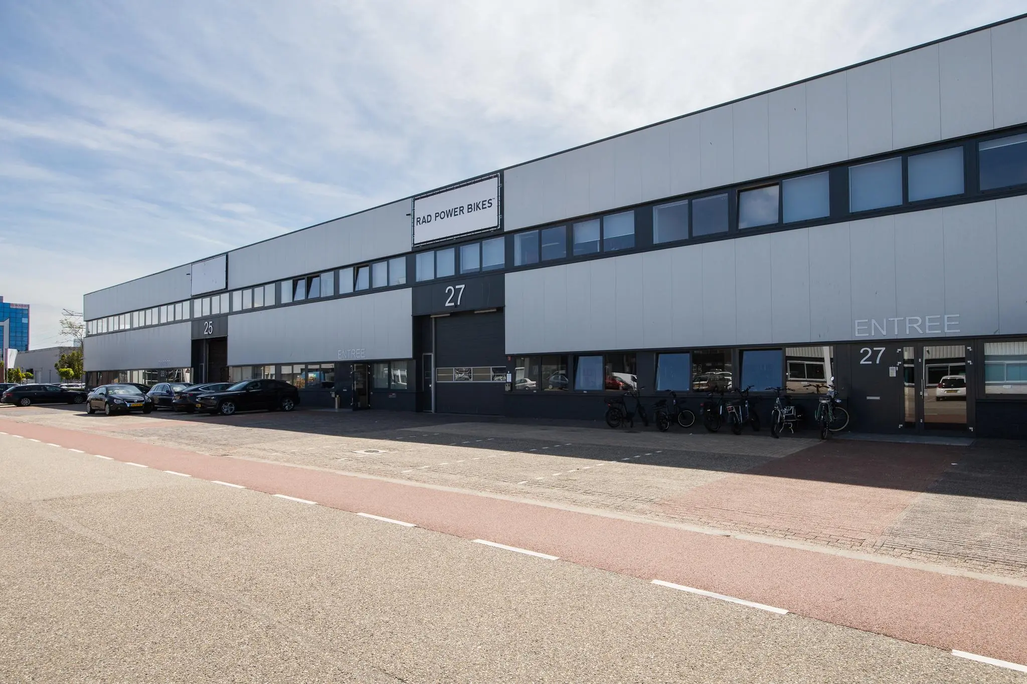 Bedrijfsgebouw aan de Zonnebaan met de ingang van Rad Power Bikes en geparkeerde fietsen en auto’s.