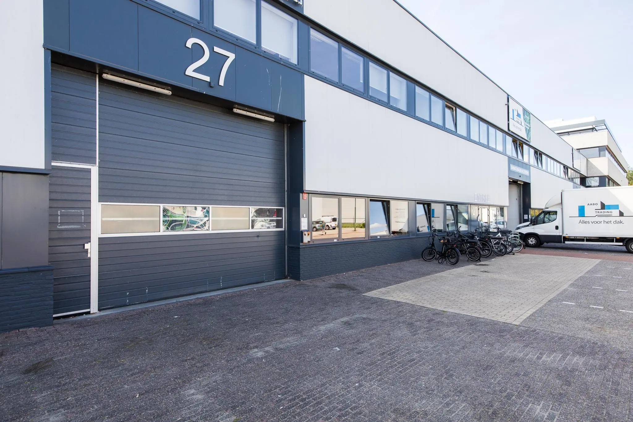 Bedrijfspand aan de Zonnebaan 27 met fietsen en een bedrijfswagen van Aabo Trading voor de entree.